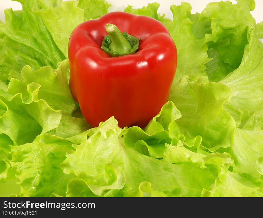 Red pepper and green leaves of salad isolated on a white background