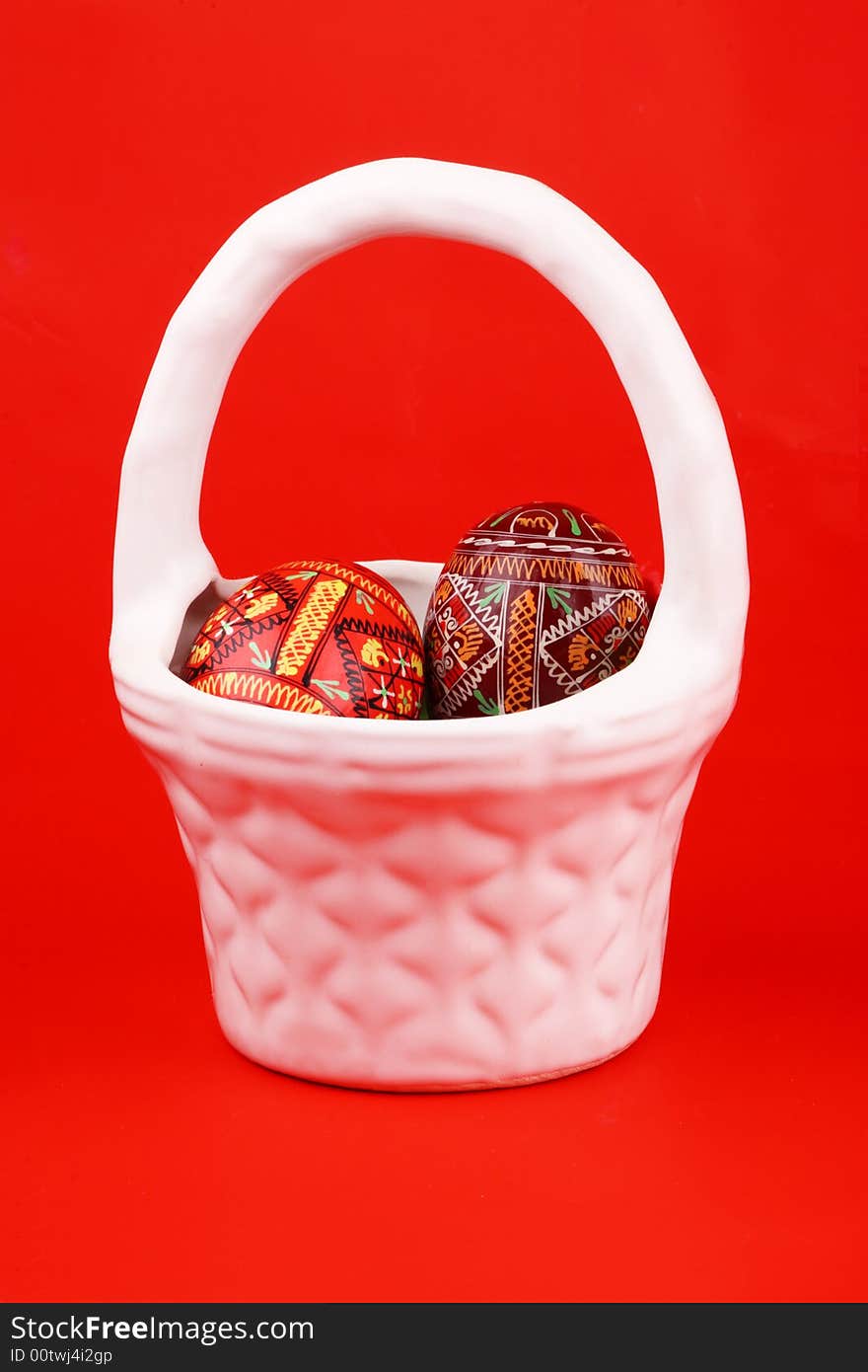 Two russian tradition easter eggs in white porcelain basket over red. Two russian tradition easter eggs in white porcelain basket over red