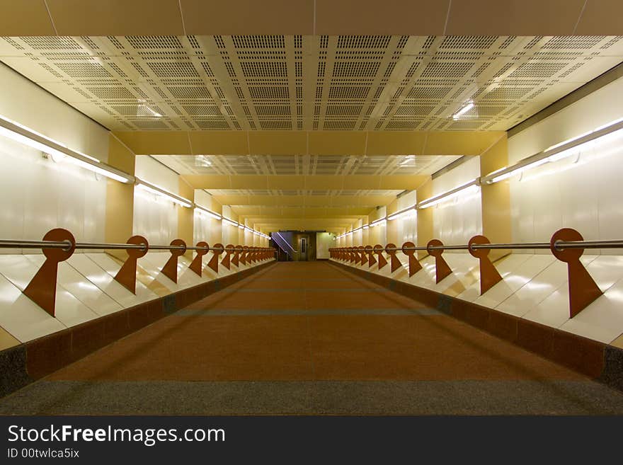 A pedestrian tunnel at a commuter rail station, with a colorful design including tinted concrete. A pedestrian tunnel at a commuter rail station, with a colorful design including tinted concrete