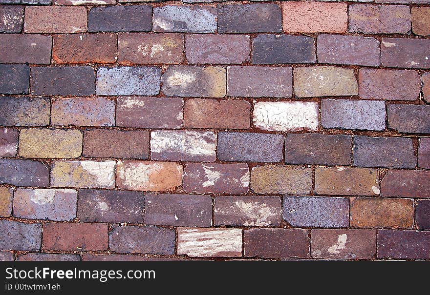 Closeup of worn, old brick paving found on a sidewalk.