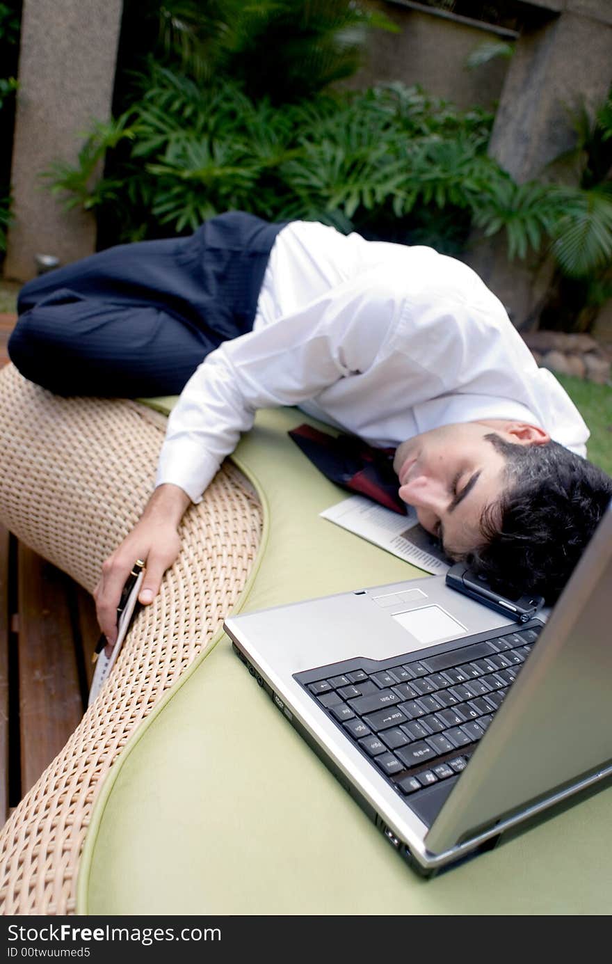 Man in business attire asleep in front of his laptop. Man in business attire asleep in front of his laptop