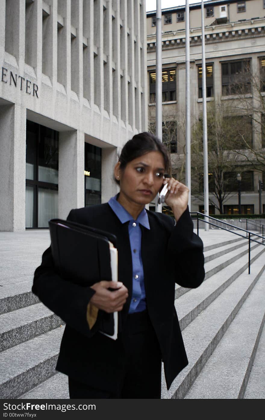 Executive Indian woman talking on a cellphone dressed in a black suit. Executive Indian woman talking on a cellphone dressed in a black suit.