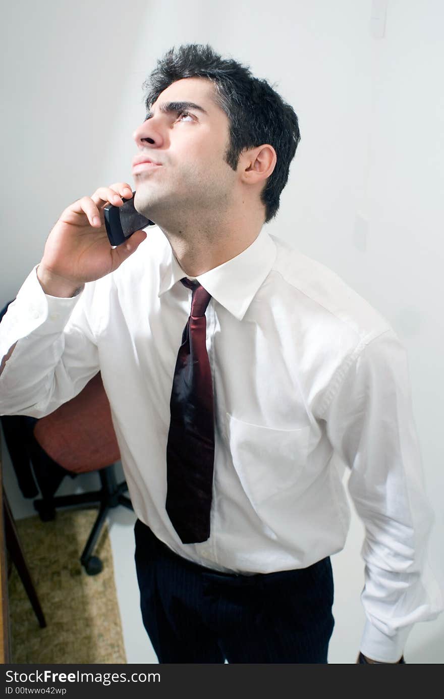 Business man looking up as he uses the phone. Isolated against a grey background. Business man looking up as he uses the phone. Isolated against a grey background