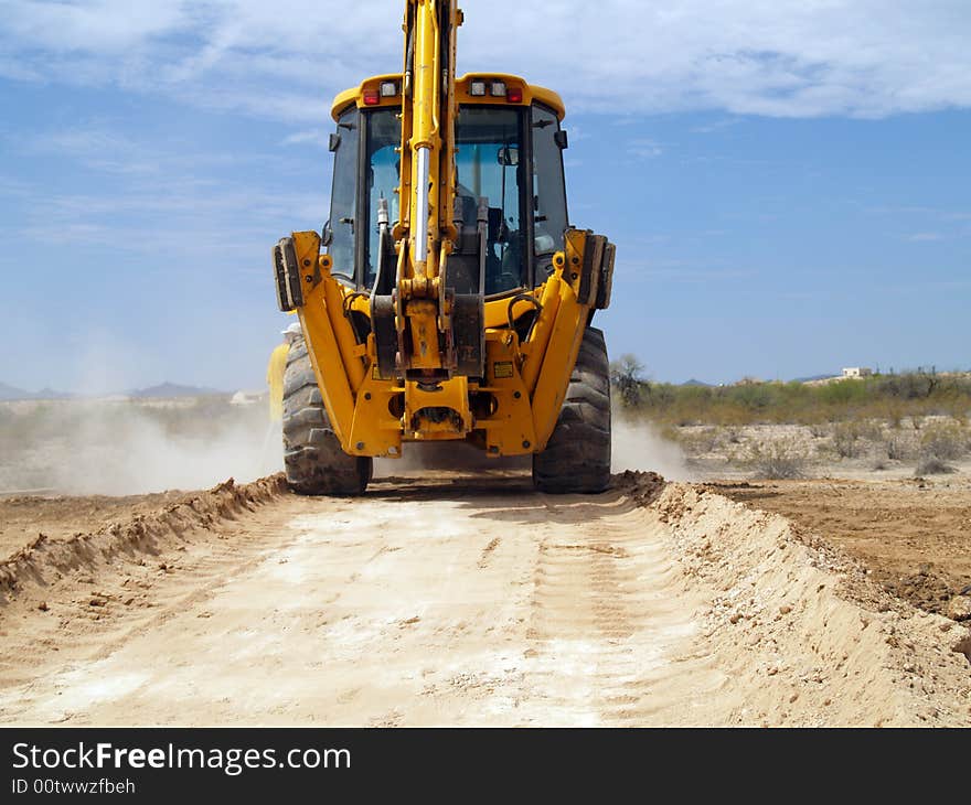 Shot of a backhoe driving down a dusty desert road. Shot of a backhoe driving down a dusty desert road.