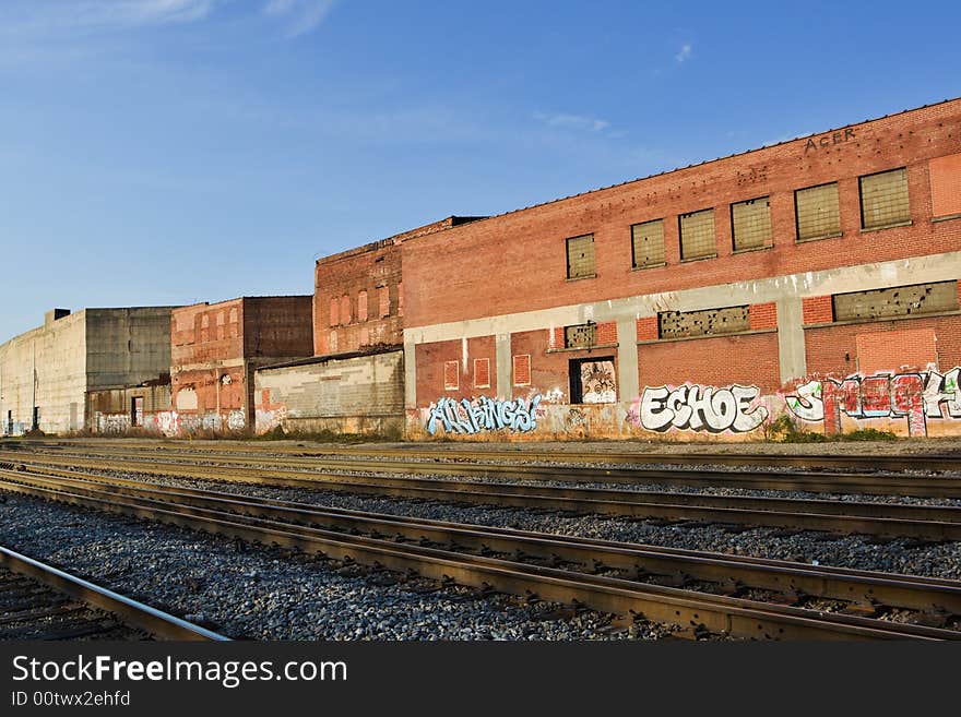 Photo of old brick warehouses with graffiti along railroad tracks. Photo of old brick warehouses with graffiti along railroad tracks
