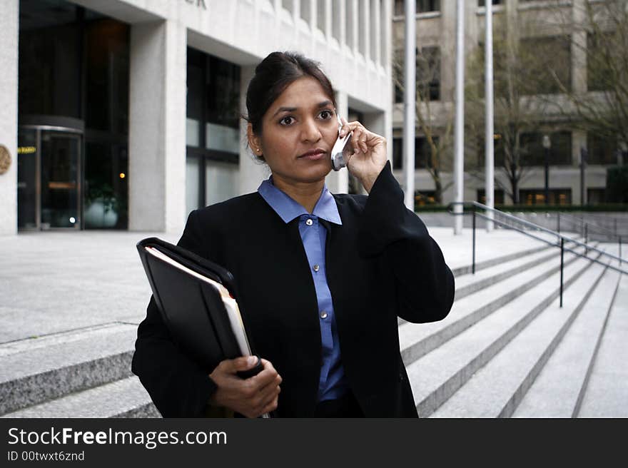 Exceutive Indian woman talking on a cellphone dressed in a black suit. Exceutive Indian woman talking on a cellphone dressed in a black suit.