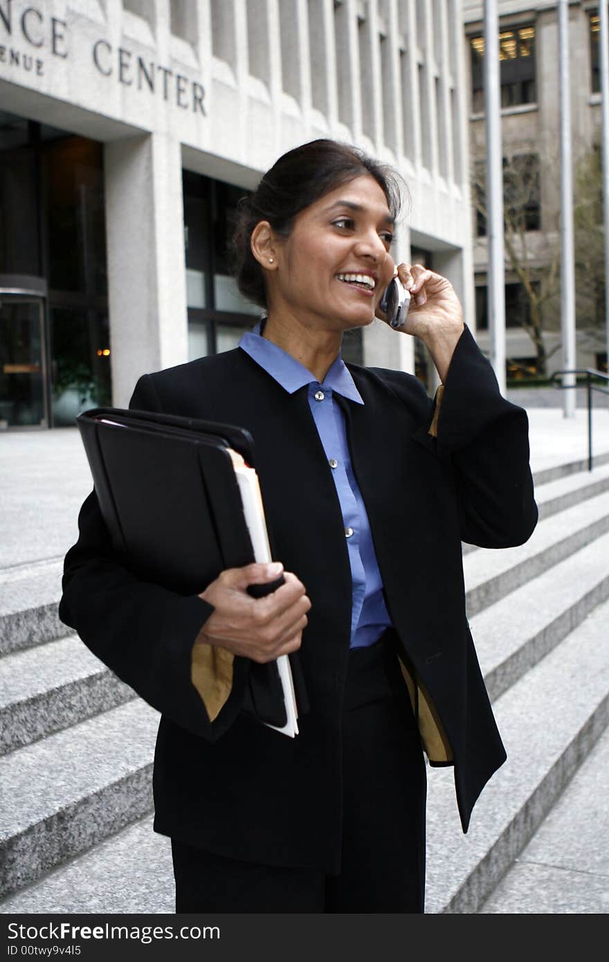 Exceutive Indian woman talking on a cellphone dressed in a black suit. Exceutive Indian woman talking on a cellphone dressed in a black suit.