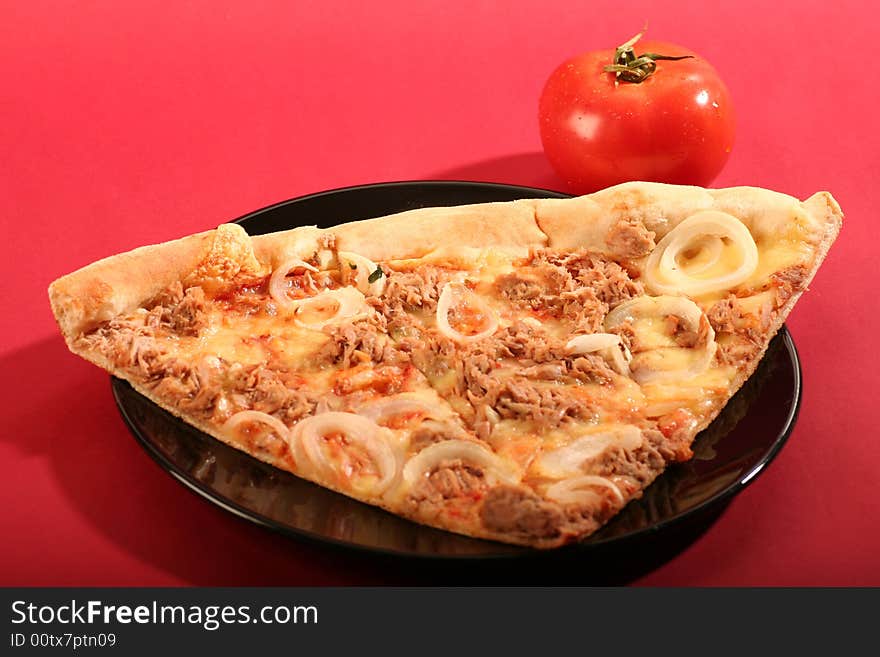 Pizza with a tomato on a red background.