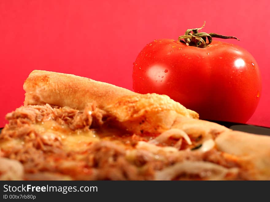 Pizza with a tomato on a red background.