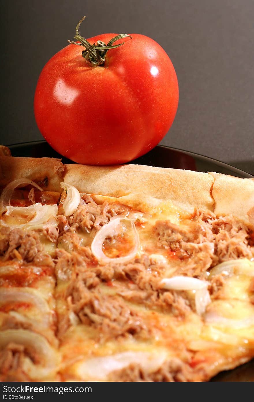 Pizza with a tomato on a red background.