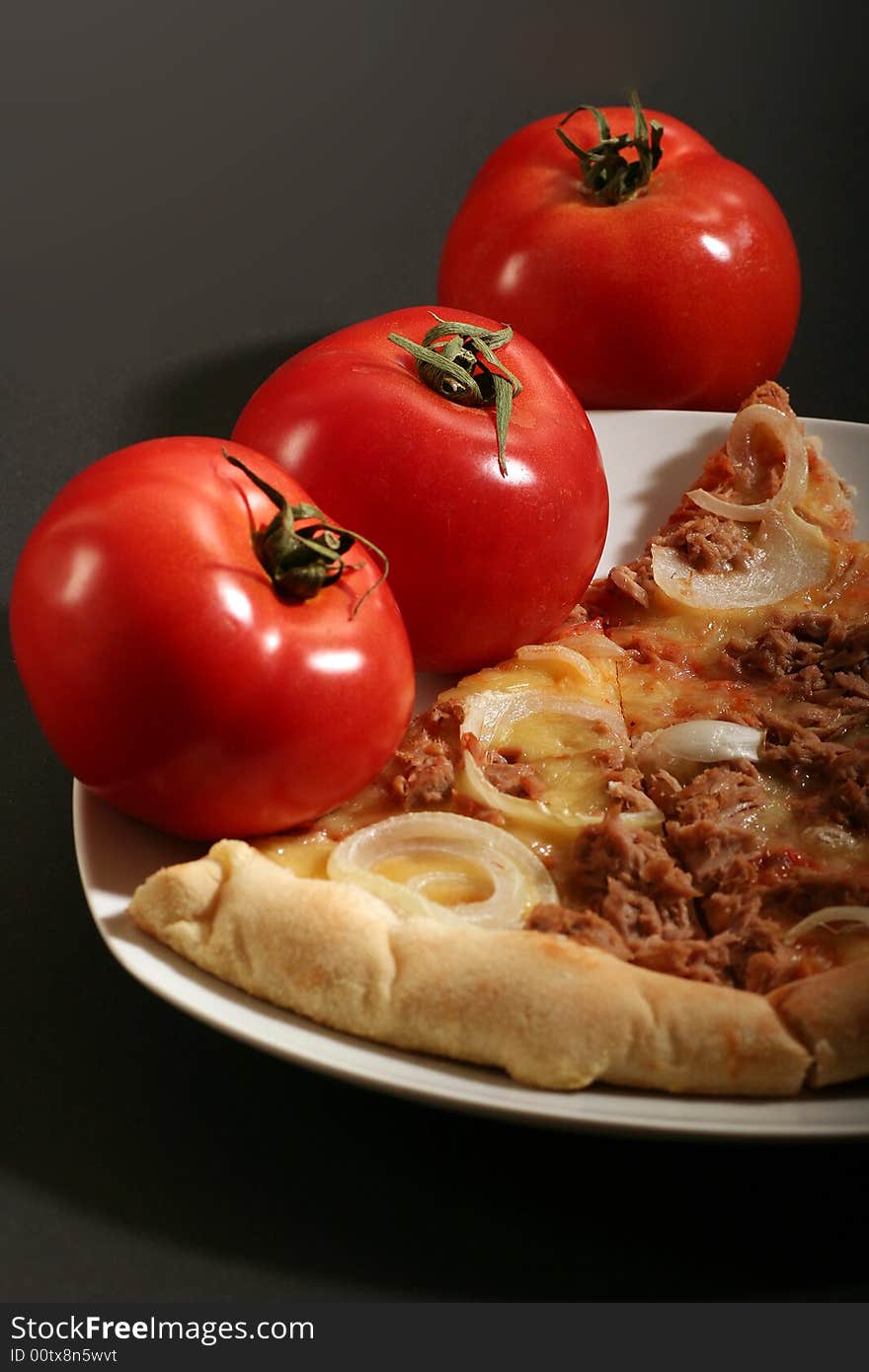 Pizza with tomatoes on a black background.