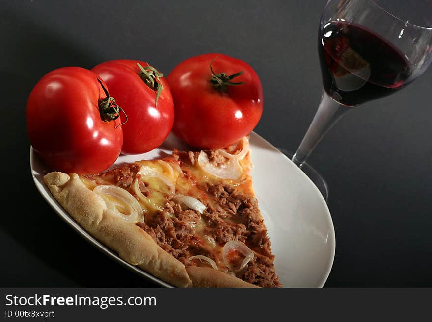 Pizza with tomatoes a glass wine on a black background.