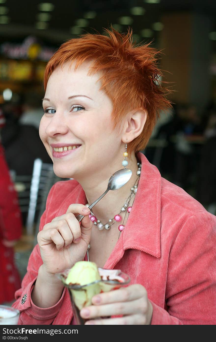 Woman eating ice-cream in cafe and thoughtfully looks afar