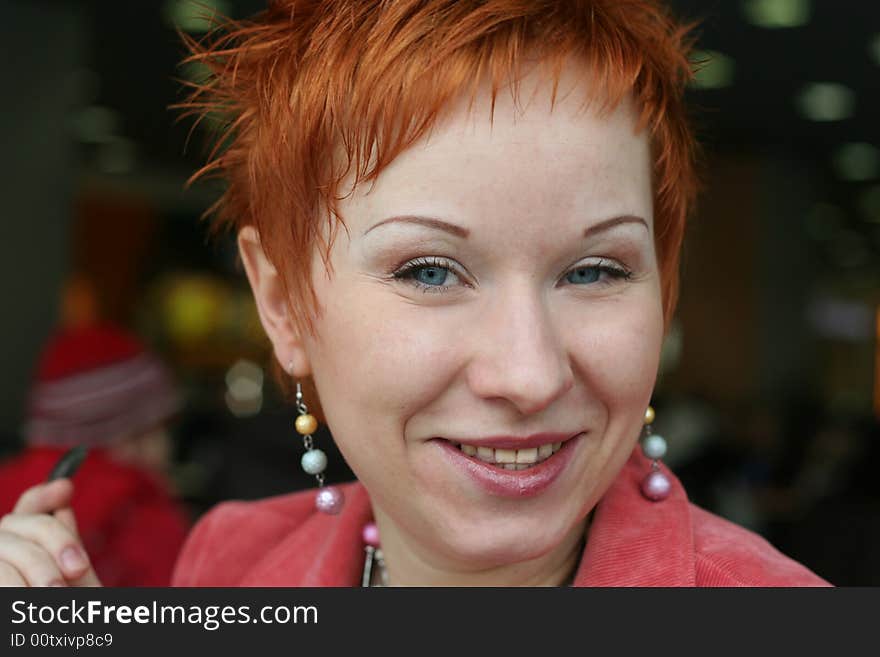 Red haired woman is smiling in cafe