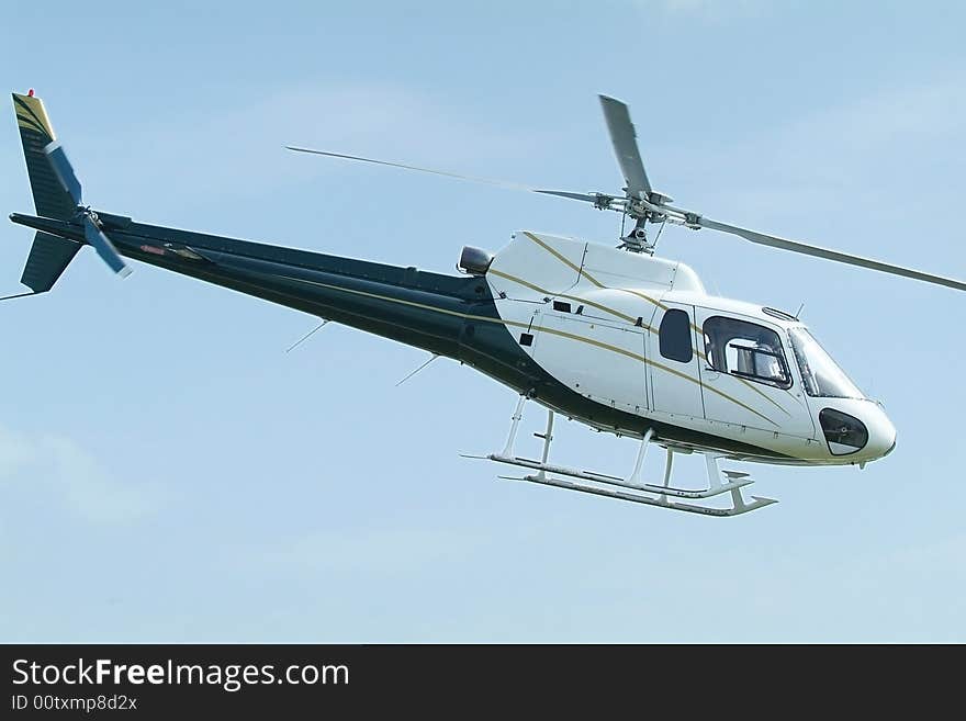 Small, blue and white, passenger helicopter mid-air. Small, blue and white, passenger helicopter mid-air