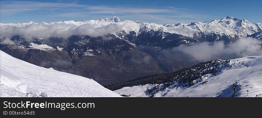 A panoramic view on Alps snow winter mountains chain under blue sky. Courchevel, France, EU. A panoramic view on Alps snow winter mountains chain under blue sky. Courchevel, France, EU.