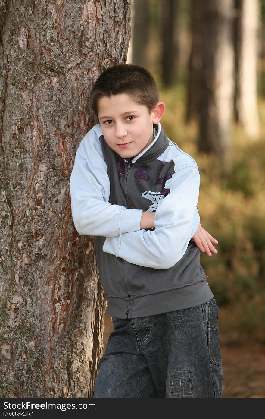 A teenage boy leaning against a tree with a look of attitude. A teenage boy leaning against a tree with a look of attitude