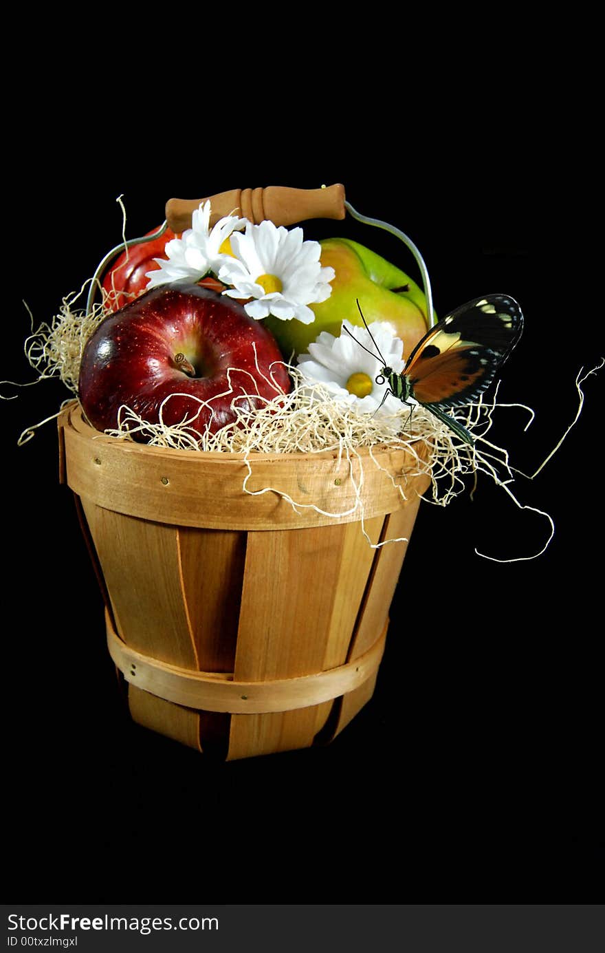 Basket of fresh apples with a butterfly and daisies on a black background. Basket of fresh apples with a butterfly and daisies on a black background.