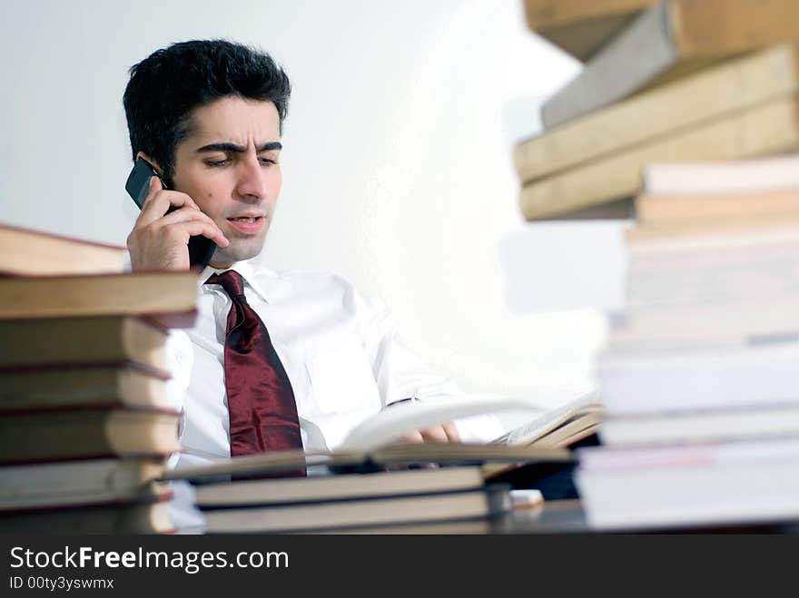 Man in business attire on the phone surrounded by books