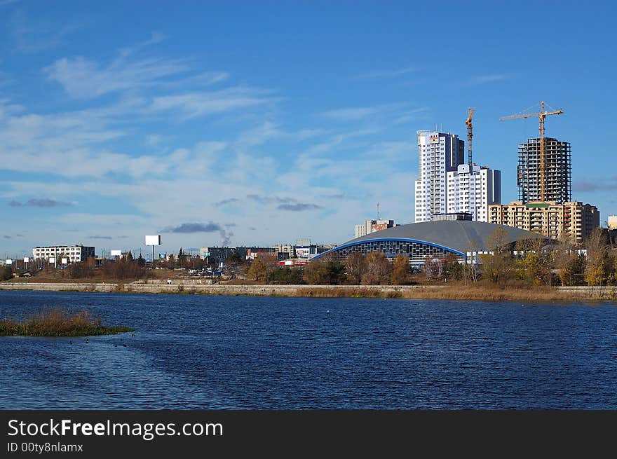 Autumn in the city, river in the foreground and blue sky as the background. Autumn in the city, river in the foreground and blue sky as the background