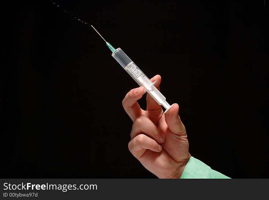 Doctor’s hand holding syringe isolated on black. Doctor’s hand holding syringe isolated on black