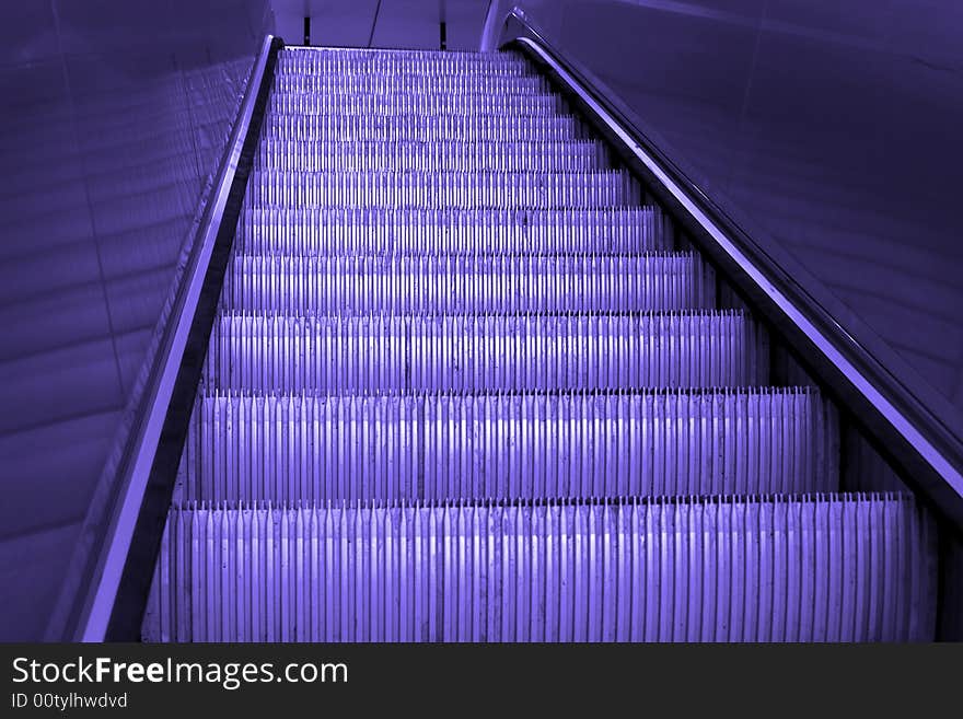 Going up a shiny metal staircase, escalator, empty, finished with blue tine