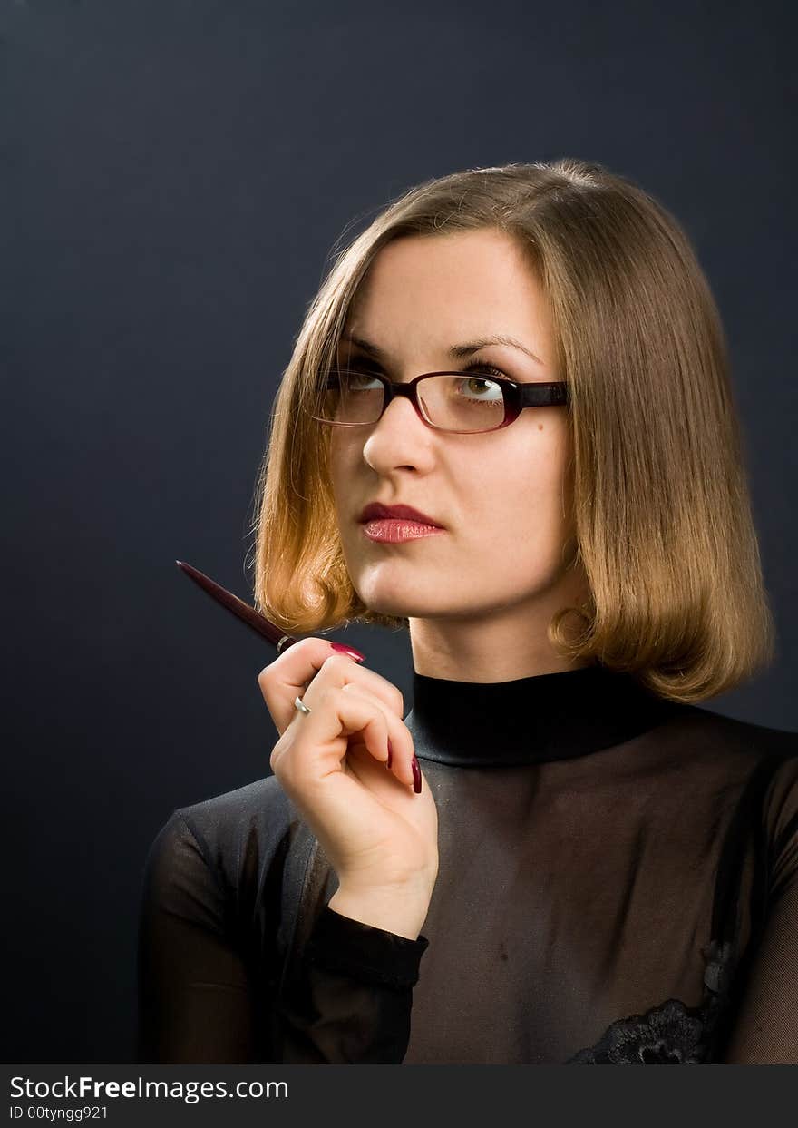 Portrait of girl with glasses and pen at hand on black background