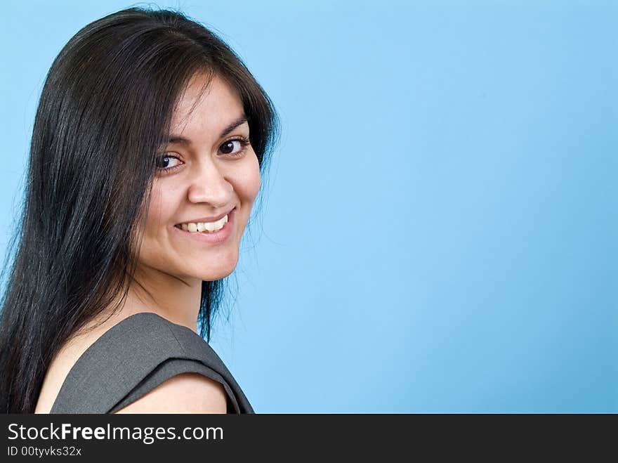 A pretty young woman smiling coyly for the camera taken against a blue background with copy space. A pretty young woman smiling coyly for the camera taken against a blue background with copy space.