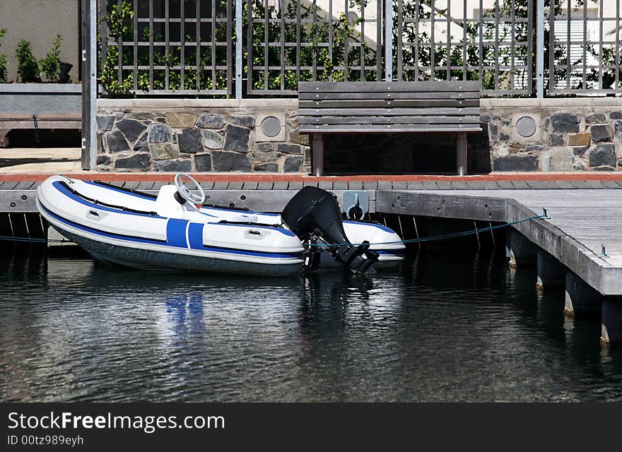 An inflatable boat tied up next to a pier. An inflatable boat tied up next to a pier