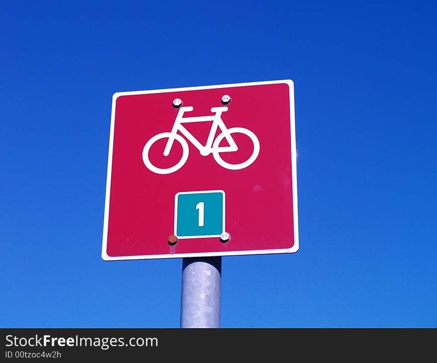 Red bicycle sign on blue sky background