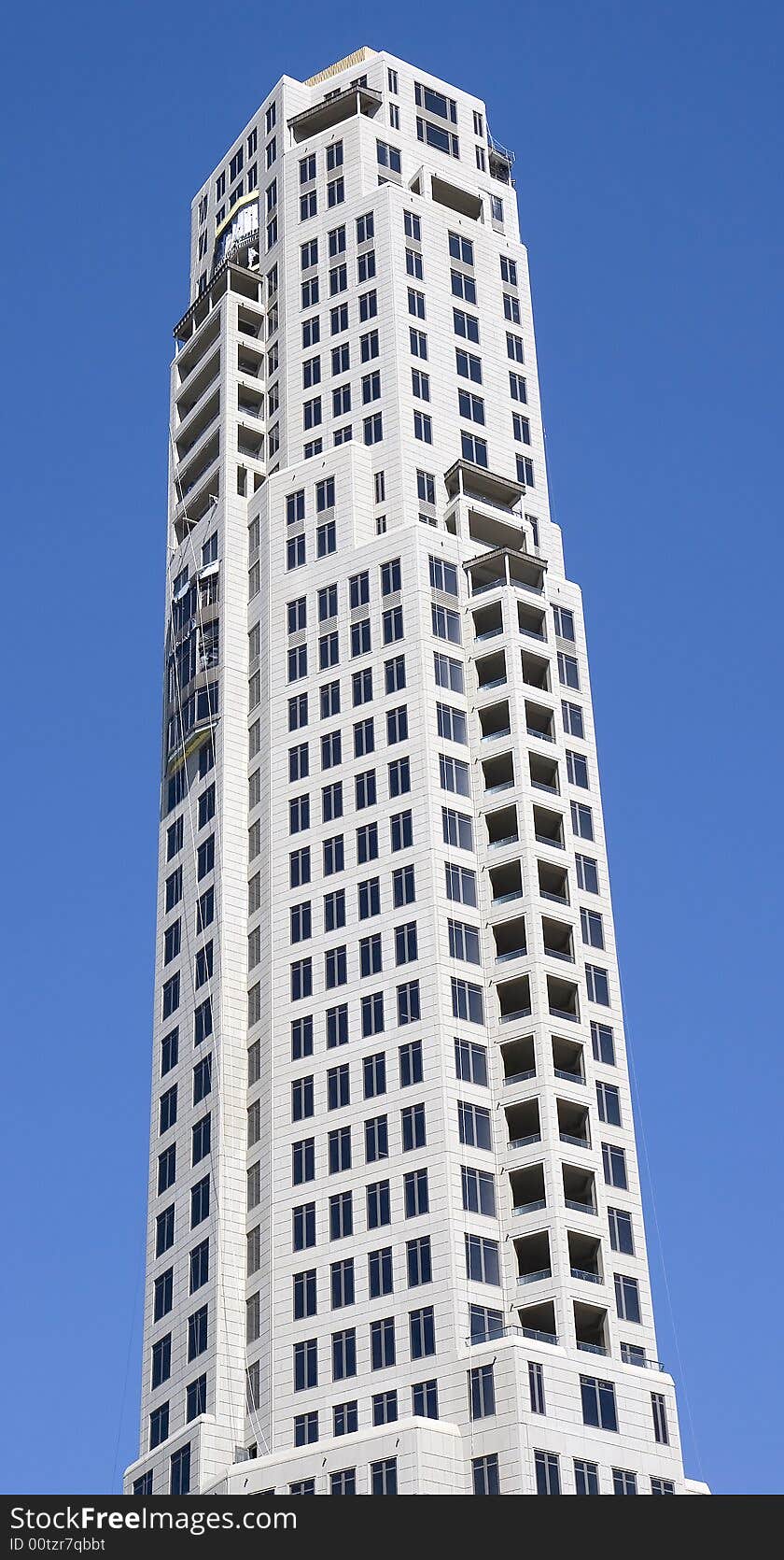 A new white condominium high rise building against a blue sky. A new white condominium high rise building against a blue sky