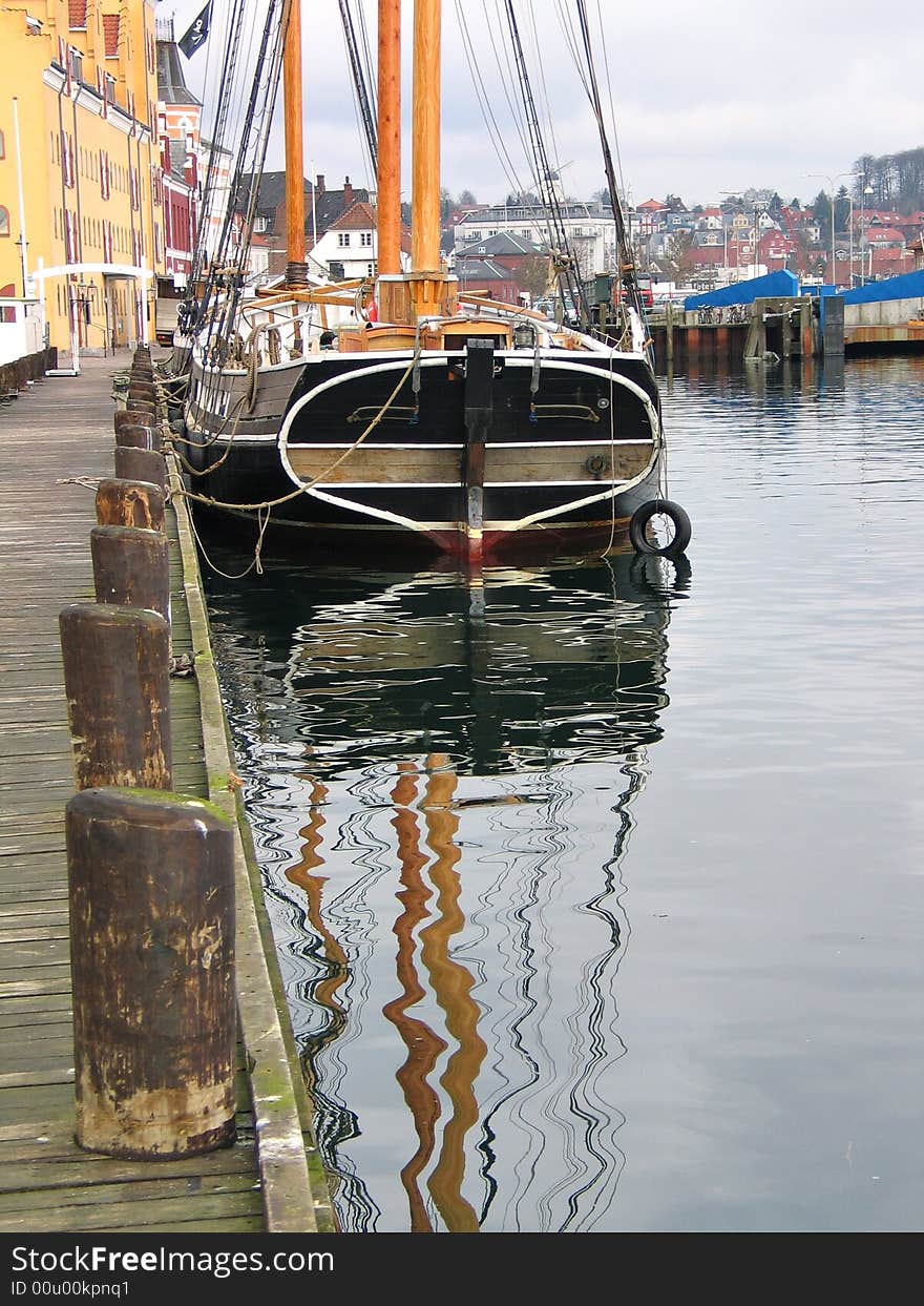 Traditional wooden tall sailboat reflected in the water in Svendborg Marina Denmark