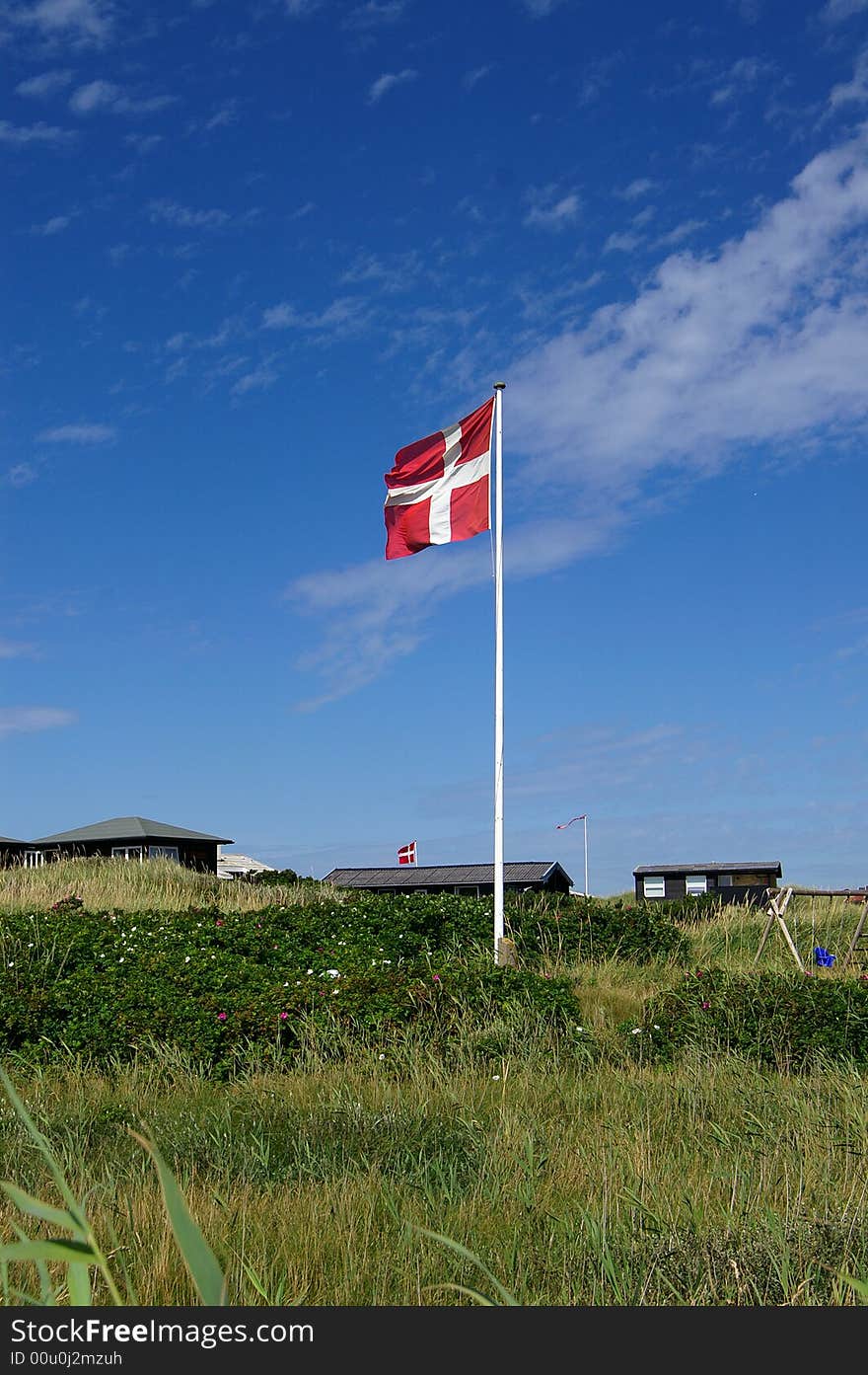 A danish flag in typical danish sommerhouse surroundings. A danish flag in typical danish sommerhouse surroundings