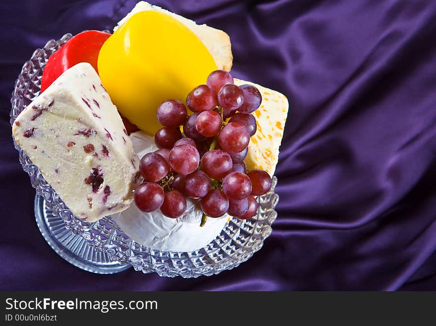 Cheese and grape selection on a purple silk background