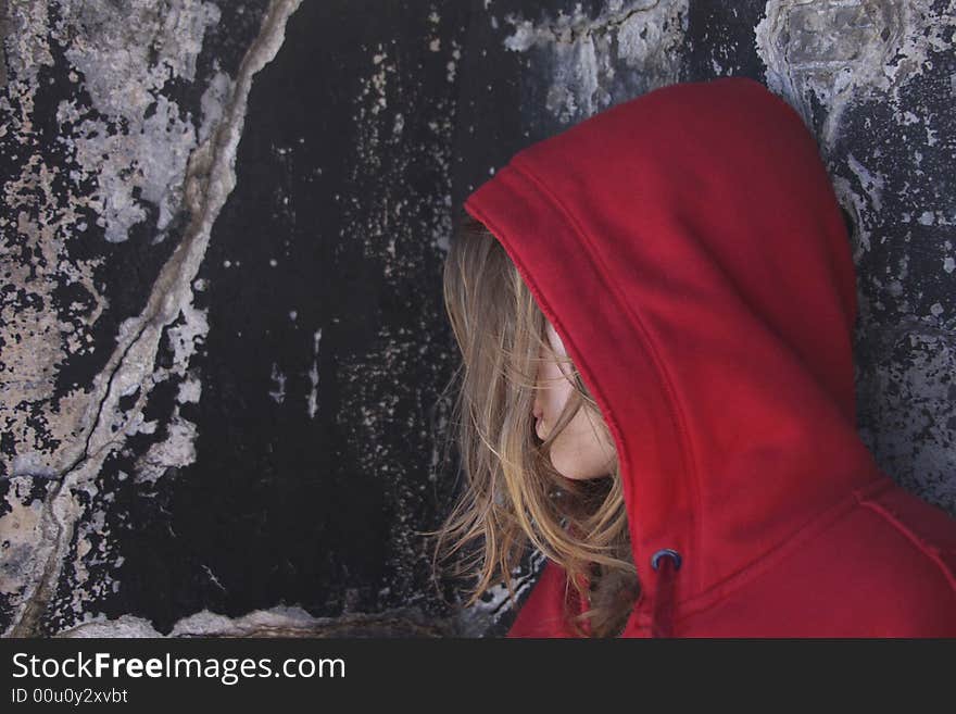 Girl in red hood leaning on ancient wall. Girl in red hood leaning on ancient wall