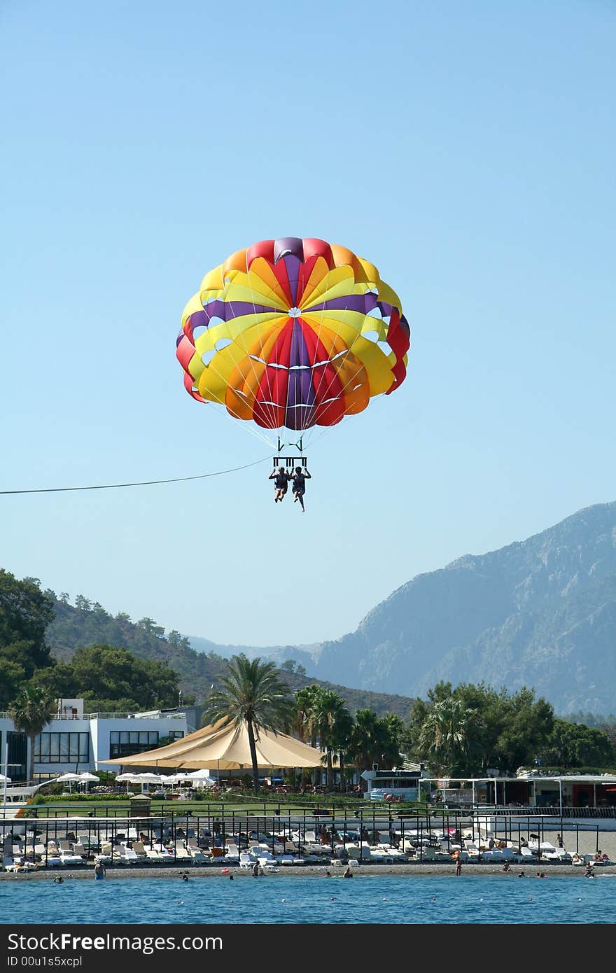 Parasail flying over the beach with pair onboard. Parasail flying over the beach with pair onboard