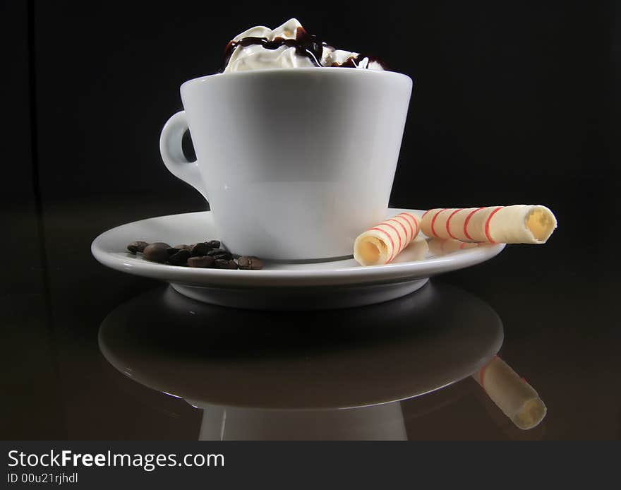 A cup of coffee with two rolls on the black background. A cup of coffee with two rolls on the black background