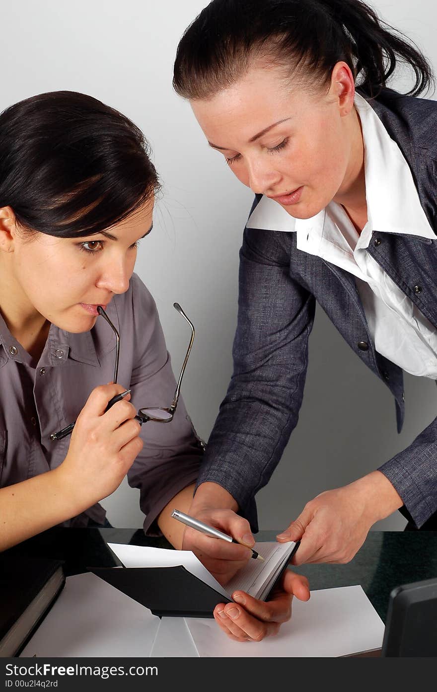 Two attractive brunette women working in office. Two attractive brunette women working in office