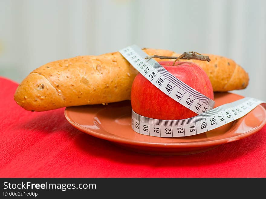 Red apple, tape measure and bread roll. Red apple, tape measure and bread roll