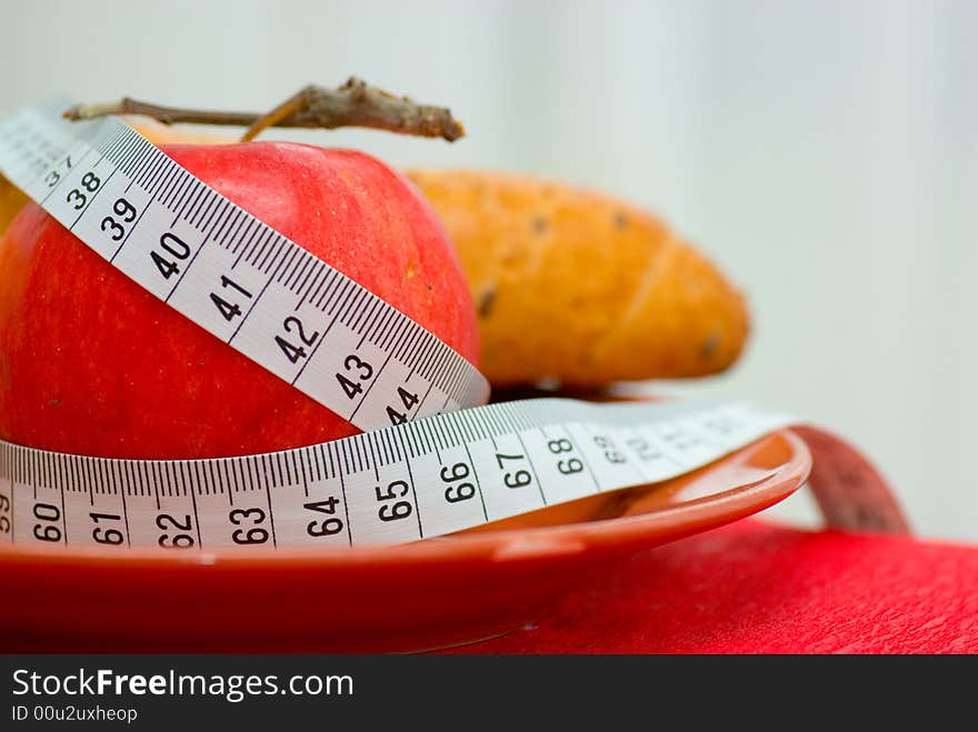 Red apple, tape measure and bread roll. Red apple, tape measure and bread roll