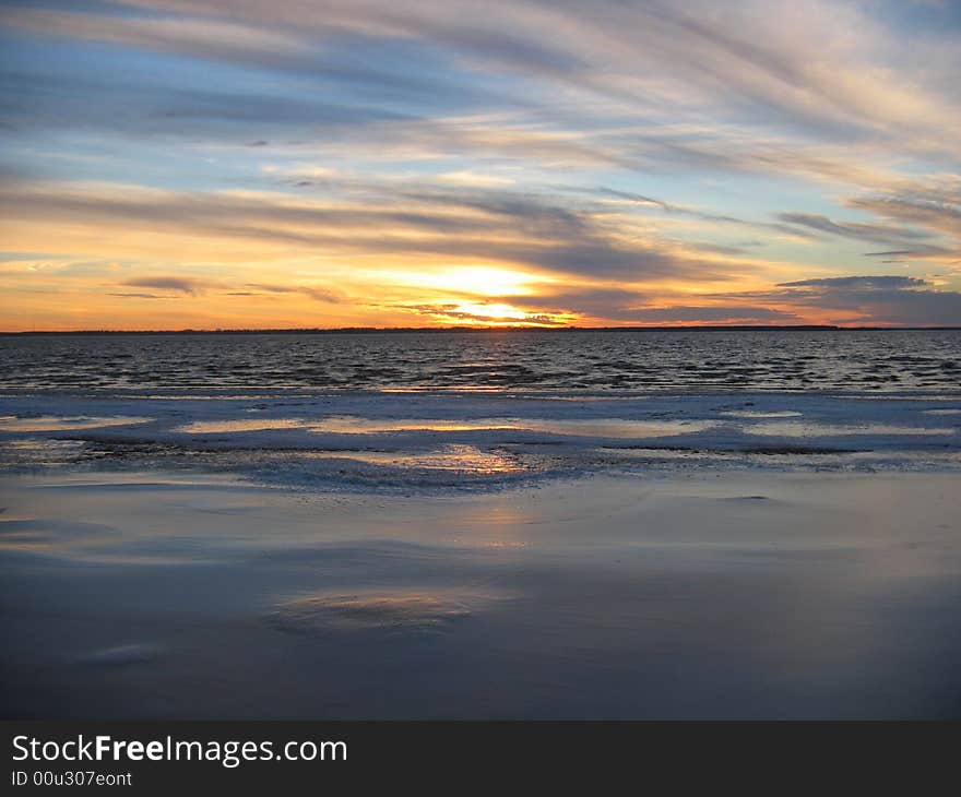 Sunset over ice river in autumn