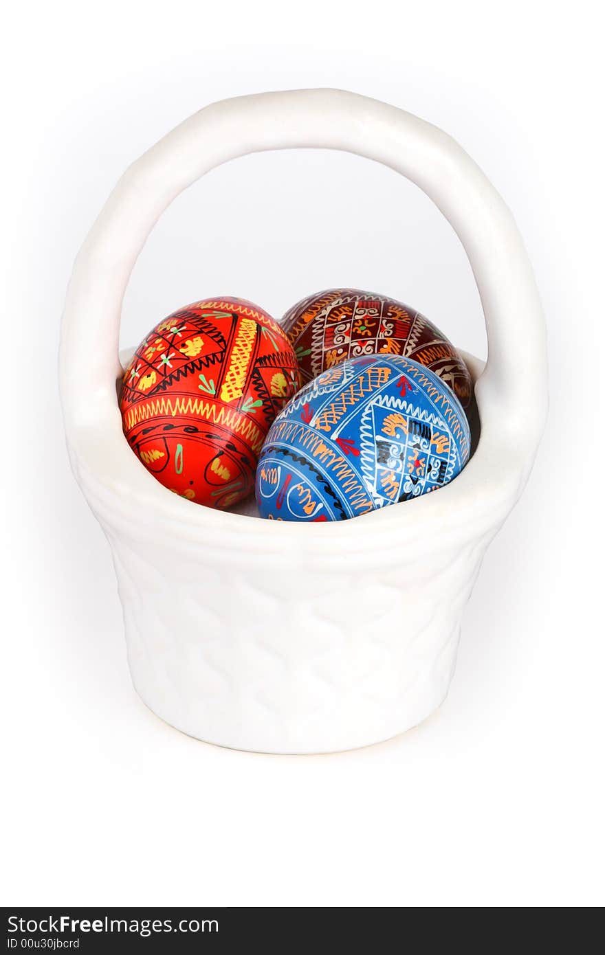 Three easter eggs in white basket over white