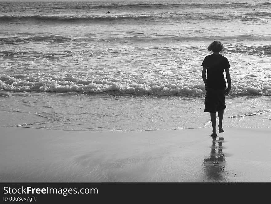 Teenage boy walking out to the ocean tide. Teenage boy walking out to the ocean tide.