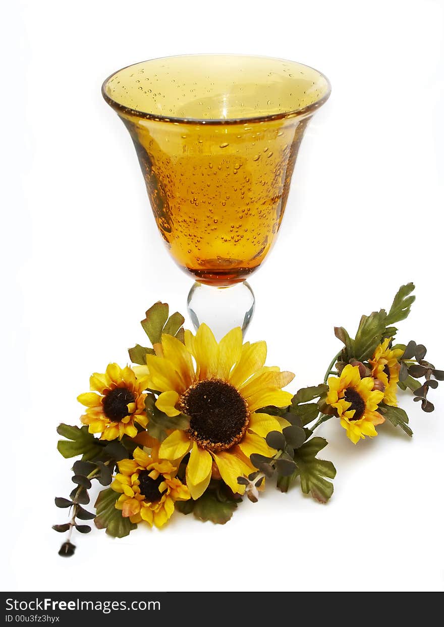 Big yellow wineglass with bouquet of artificial sunflower isolated with white background. Big yellow wineglass with bouquet of artificial sunflower isolated with white background