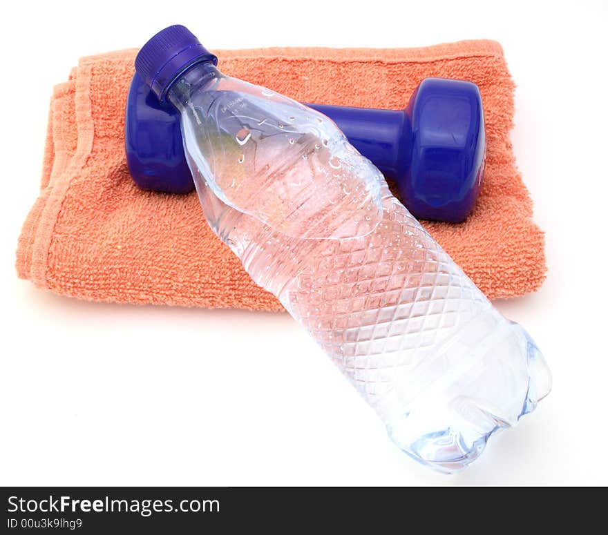 Water bottle and a blue dumbbell over a towel in a white surface. Water bottle and a blue dumbbell over a towel in a white surface