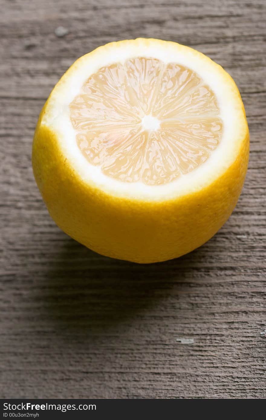 Half of sour yellow lemon laying on the old wooden table vertical. Half of sour yellow lemon laying on the old wooden table vertical