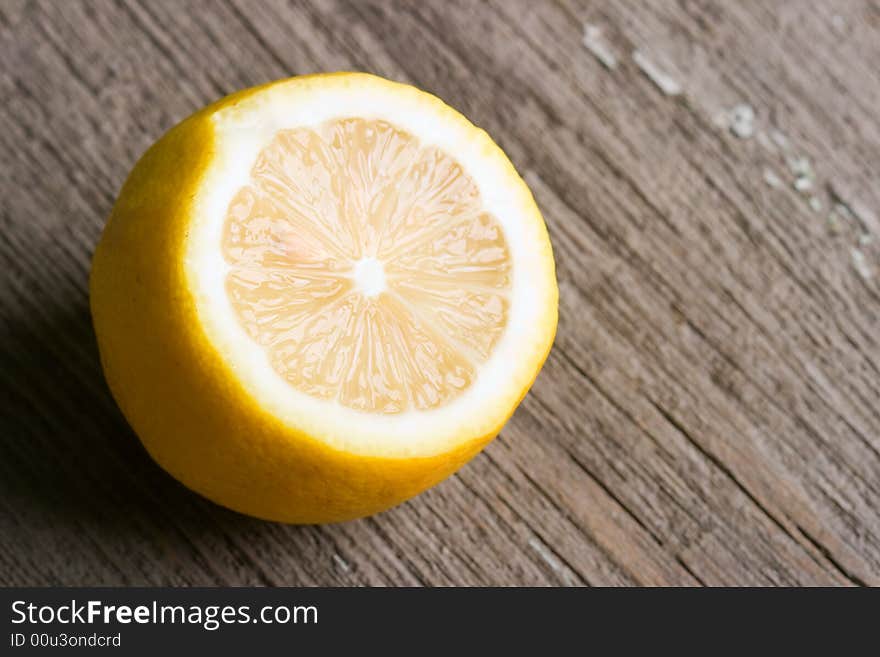 Half of sour yellow lemon laying on the old wooden table. Half of sour yellow lemon laying on the old wooden table