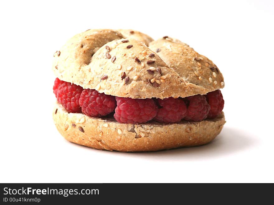 Fresh baked whole grain roll with raspberry on white background.