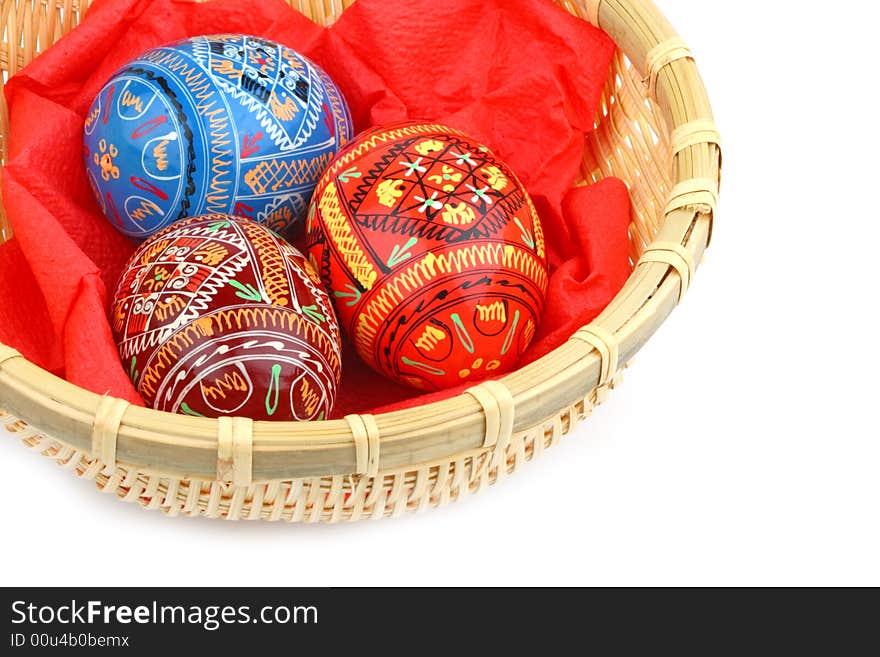 Three russian tradition easter eggs in yellow basket close up over white