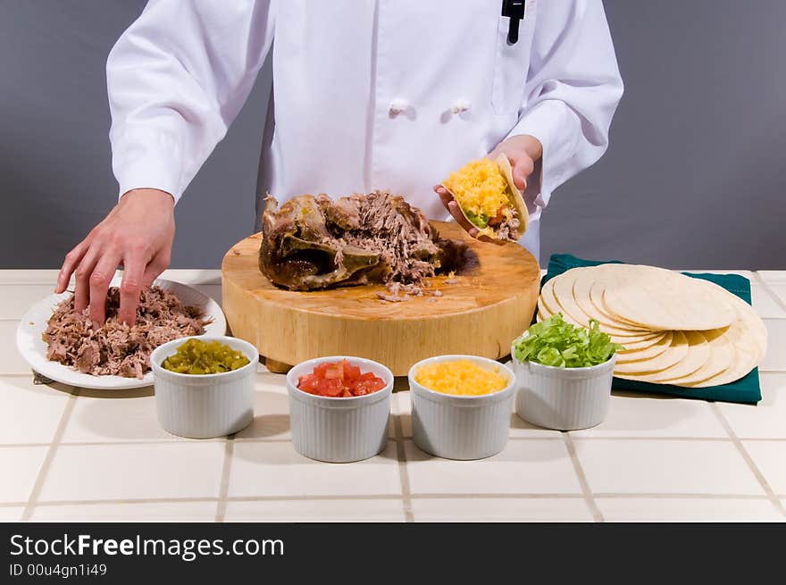 Close up portrait of a uniformed female Chef preparing a juicy pork roast soft shell taco. Close up portrait of a uniformed female Chef preparing a juicy pork roast soft shell taco.